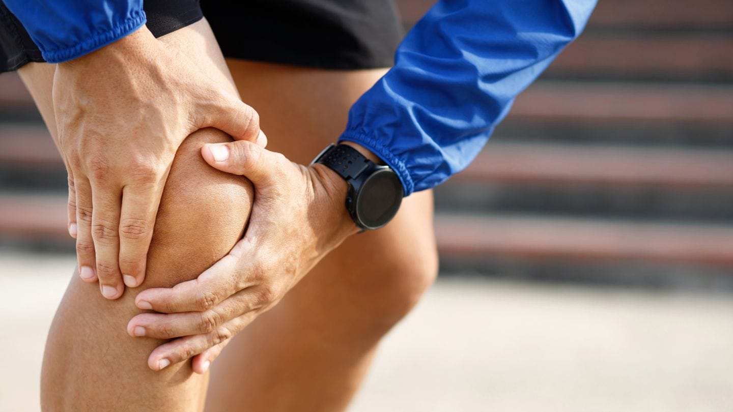 Male runner holding knee with patellofemoral pain syndrome